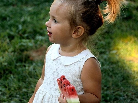 Kind hält eine Melone in der Hand